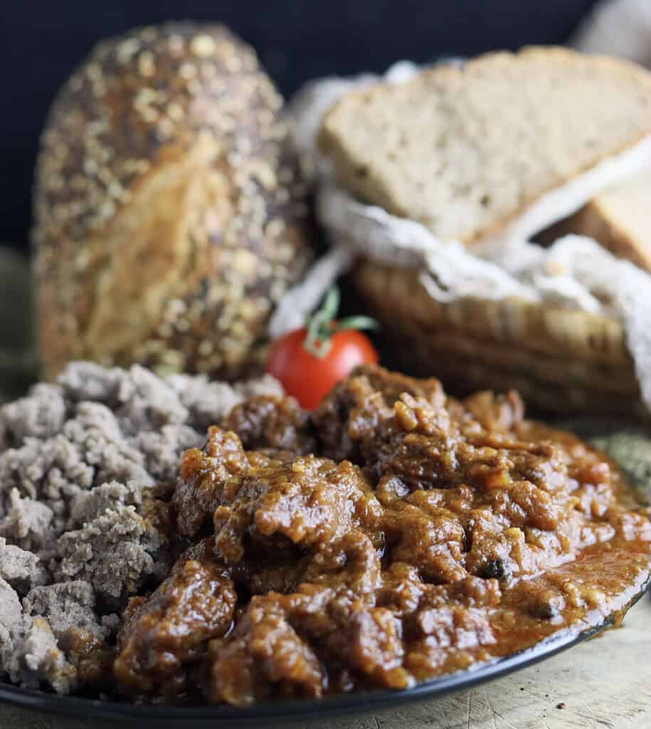 Cooked gulasz wolowy (polish beef goulash with homemade bread in the background